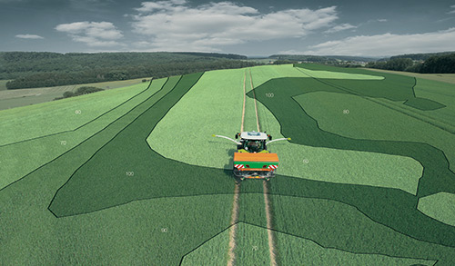 Ein Traktor fährt durch ein grünes Feld mit kartierten und nummerierten Zonen auf den Feldern.