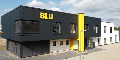Modernes zweistöckiges Gebäude mit schwarz-weißem Äußeren und großem gelben BLU-Schild an der oberen Fassade.