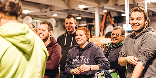 Eine Gruppe von lächelnden und lachenden Menschen in einem Raum, der wie eine gesellschaftliche oder öffentliche Veranstaltung aussieht.