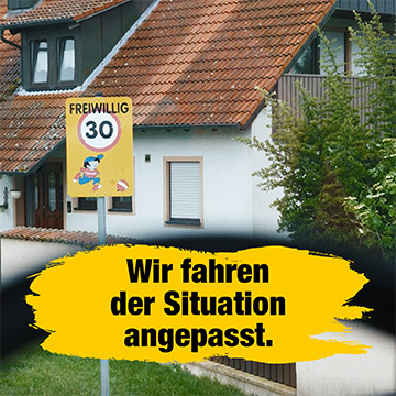 Ein Schild mit der Aufschrift Freiwillig 30 in der Nähe eines Hauses; darunter steht Wir fahren der Situation angepasst.