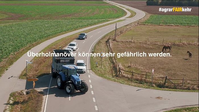 Ein Traktor biegt auf eine Landstraße ein, während sich Autos nähern; ein Text in deutscher Sprache warnt vor gefährlichen Überholmanövern.