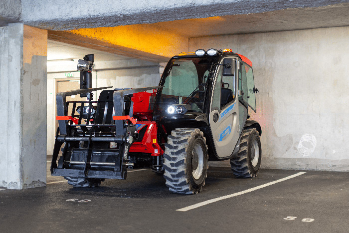 Ein Traktor ist in einem Betonparkhaus unter einer niedrigen Decke abgestellt.