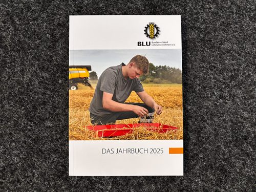 Ein junger Mann untersucht Pflanzen in einem Weizenfeld auf dem Cover von Das Jahrbuch 2025 von BLU.